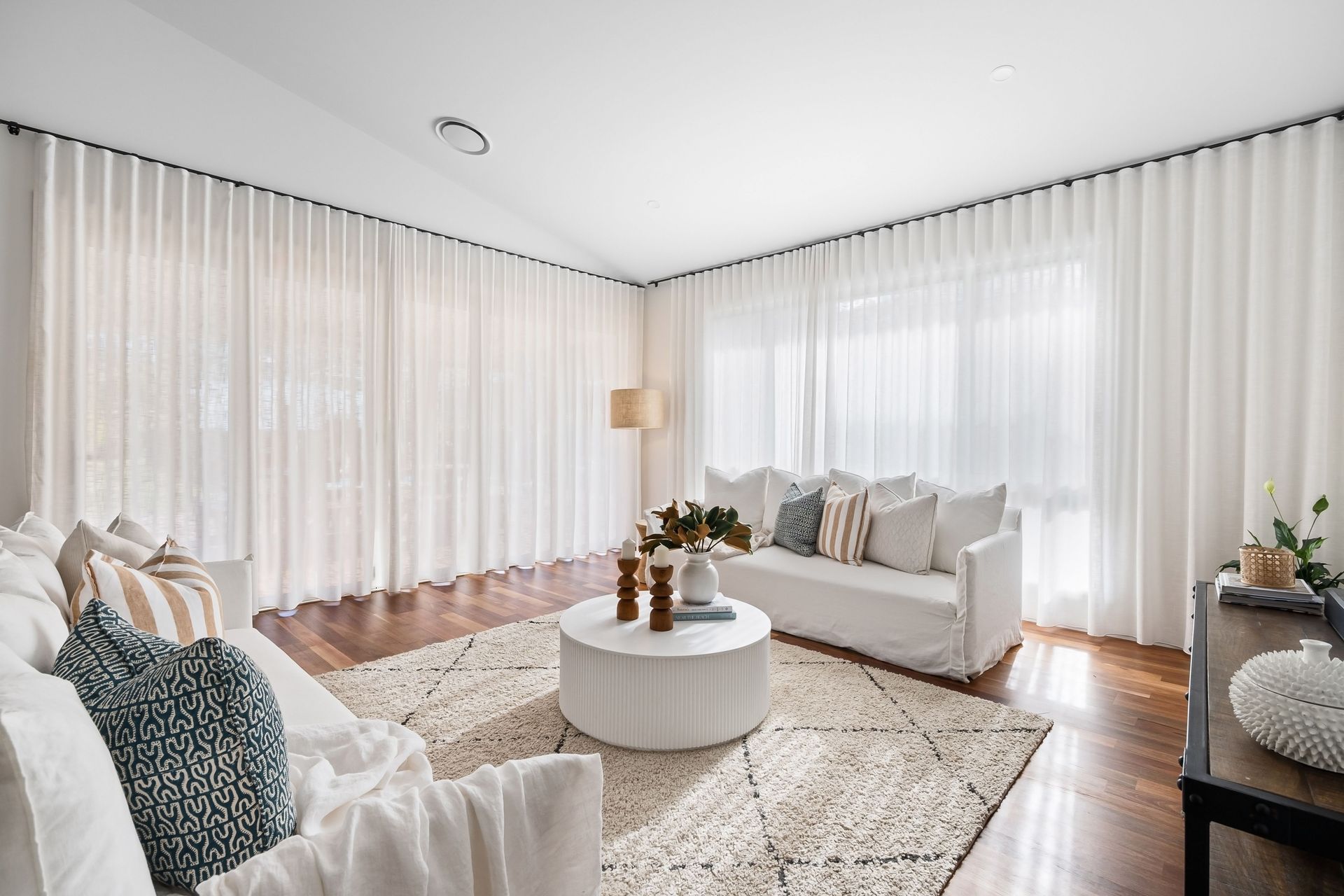 A living room in daylight, sheer curtains drawn back, nothing out of place.